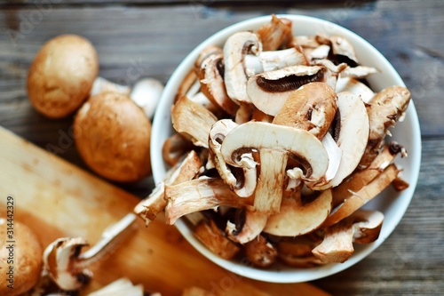Royal fresh mushrooms on a wooden background. Sliced ​​champignons in a white bowl. Cooking process.