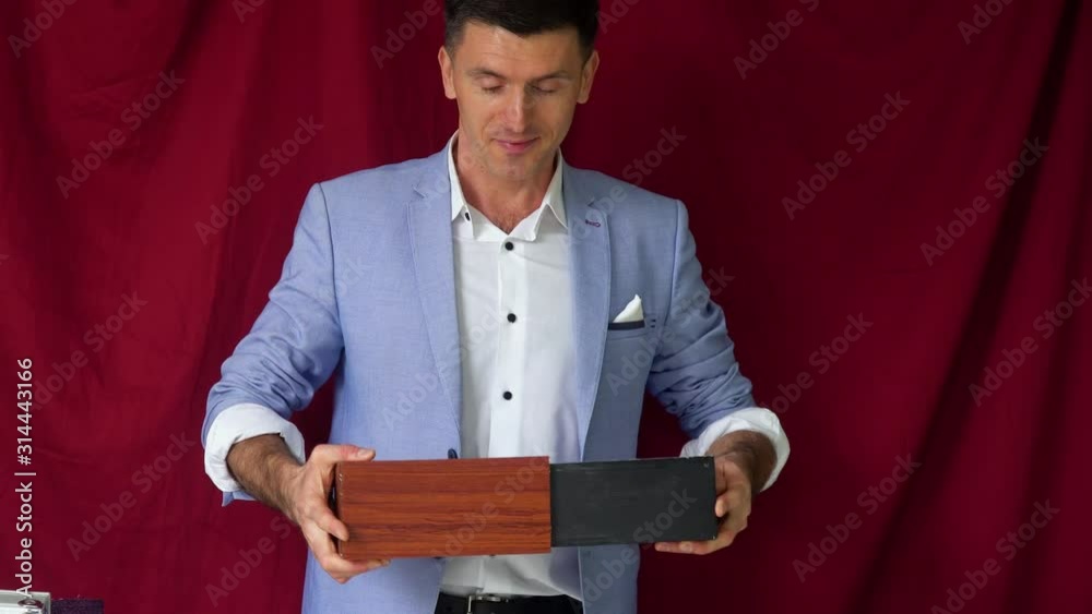 Magician in a suit shows a trick with pigeon on a vinous background