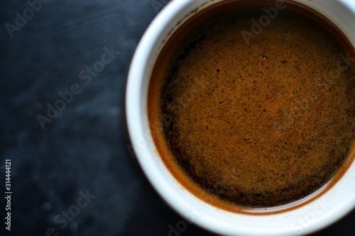 Natural coffee in a white cup. Coffee top view. Coffee with cream on a dark  dark blue background. Place for text.