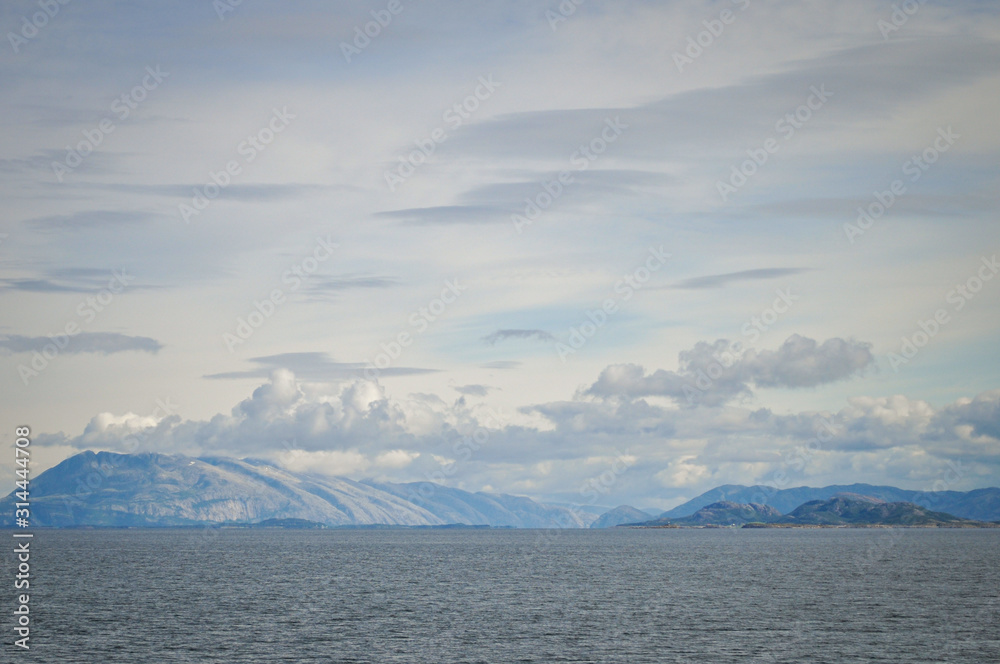 View to the cloudy sky over the sea and Vega archipelago mountains from a ferry deck in Nordland county, Norway on summer day