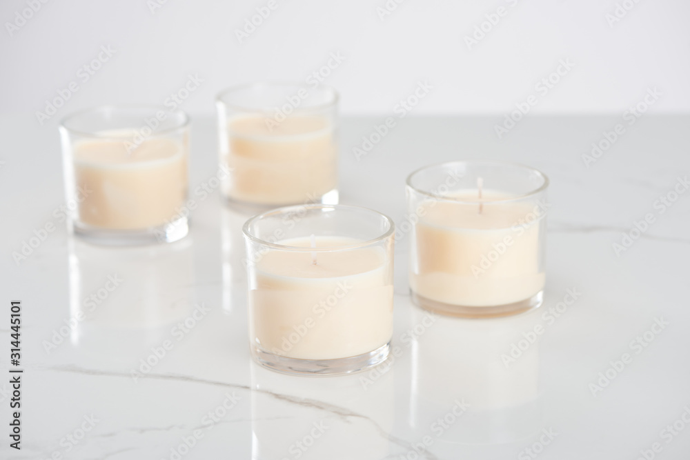 selective focus of white candles in glass on marble white surface selective focus of white candles in glass on marble white surface