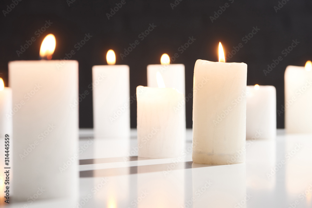 selective focus of burning white candles on white surface glowing isolated on black - obrazy, fototapety, plakaty 