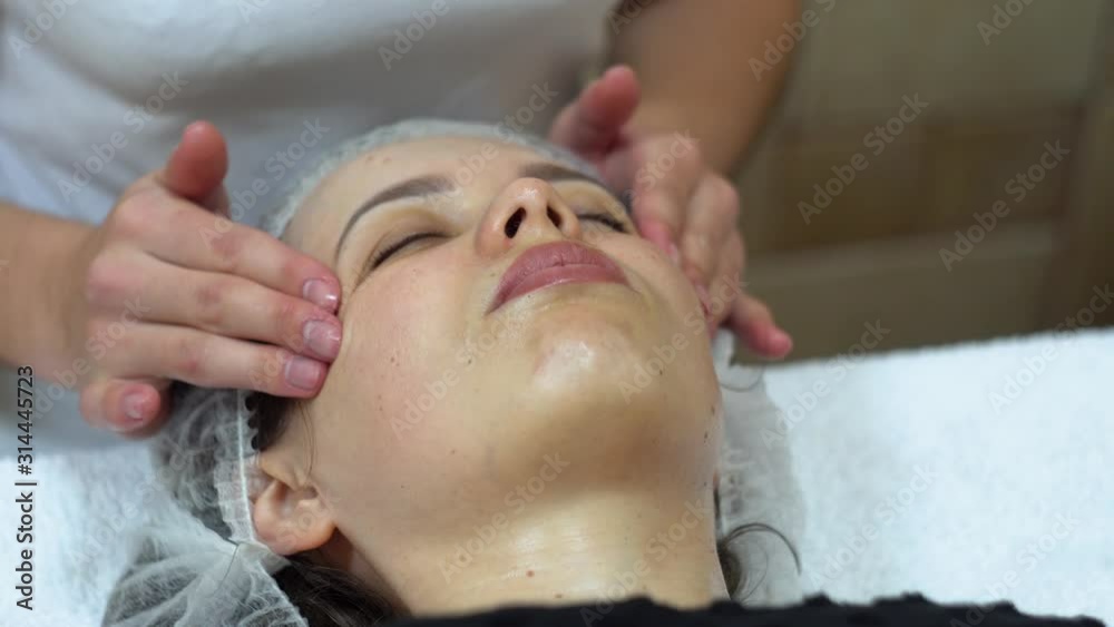 Massage therapist is doing manual massage on client's face. Spa facial massage Massage therapist is doing manual massage on client's face. Spa facial massage