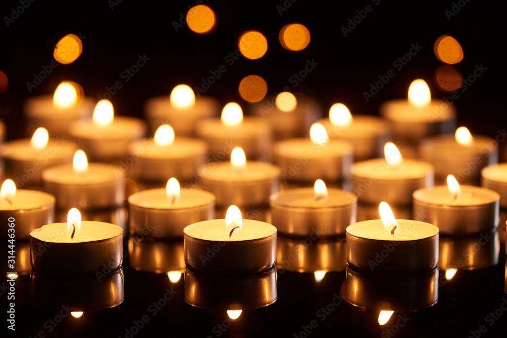 selective focus of burning candles glowing in darkness with bokeh lights selective focus of burning candles glowing in darkness with bokeh lights
