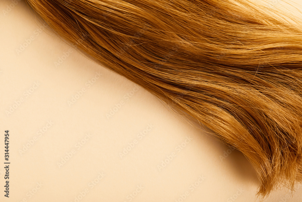 Naklejka premium Top view of brown hair on beige background