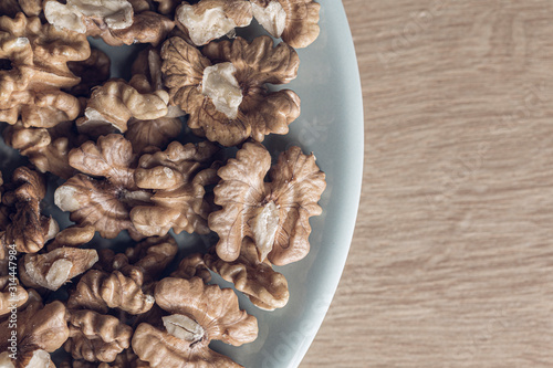 Many peeled walnuts on a blue plate close up still photo