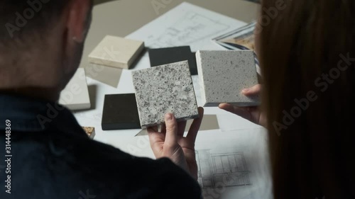 Man and woman choosing material samples close up. Team of architects discussing quartz materials for countertops in the kitchen. Artificial stone examples 4k