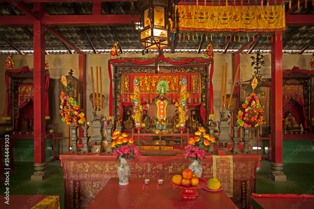 Temple bouddhiste laqué rouge et or avec offrandes à Hong-Kong.