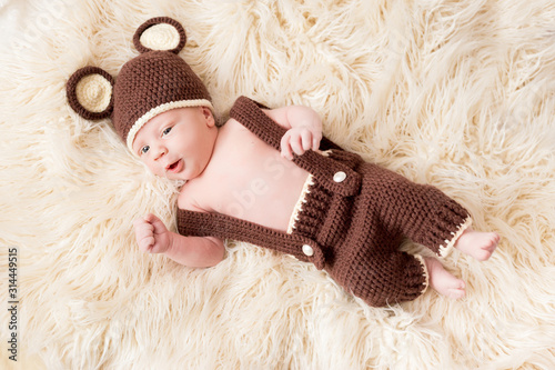 Cute little happy baby lies in a bear costume on a white background. newborn in a hat with ears on a white background