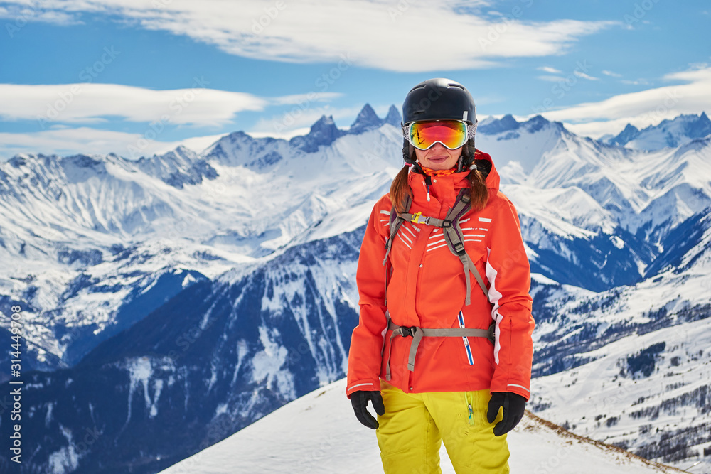 Confident woman skier posing for a portrait in the French Alps, Les Sybelles ski domain, France, on a sunny day with perfect skiing weather. Copy space on the left.