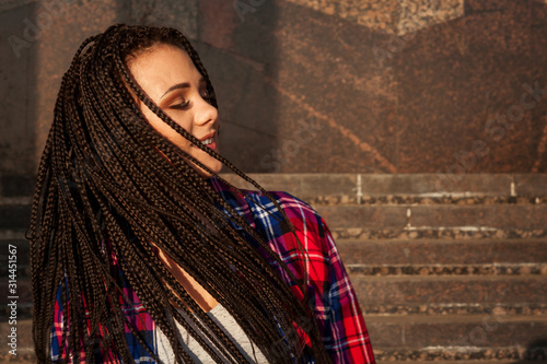 Happy beautiful young woman with afrokos in summer outdoors, close-up portrait photo