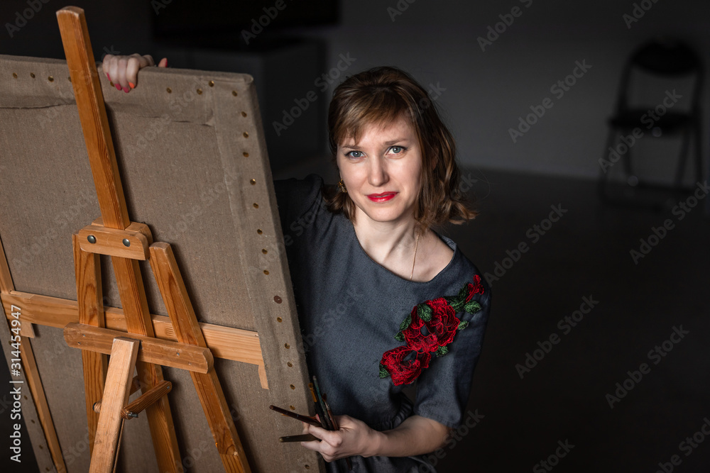 ortrait of a young artist girl who draws picture behind an easel. The ...