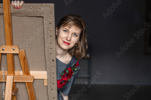 ortrait of a young artist girl who draws picture behind an easel.  The concept of hobby, creative rest. photo