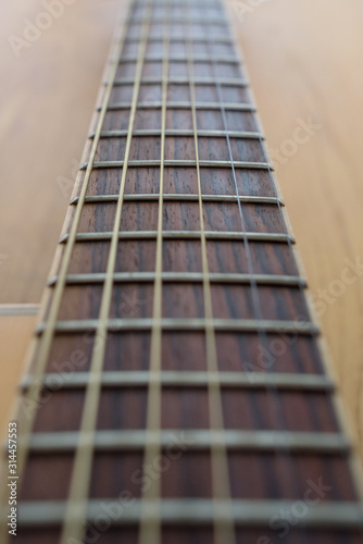 Closeup of guitar neck with six strings over a wooden background