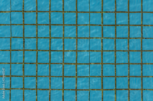 Beautiful texture of water with sun lights in a pool on the blue background of texture of small square ceramic tile photo