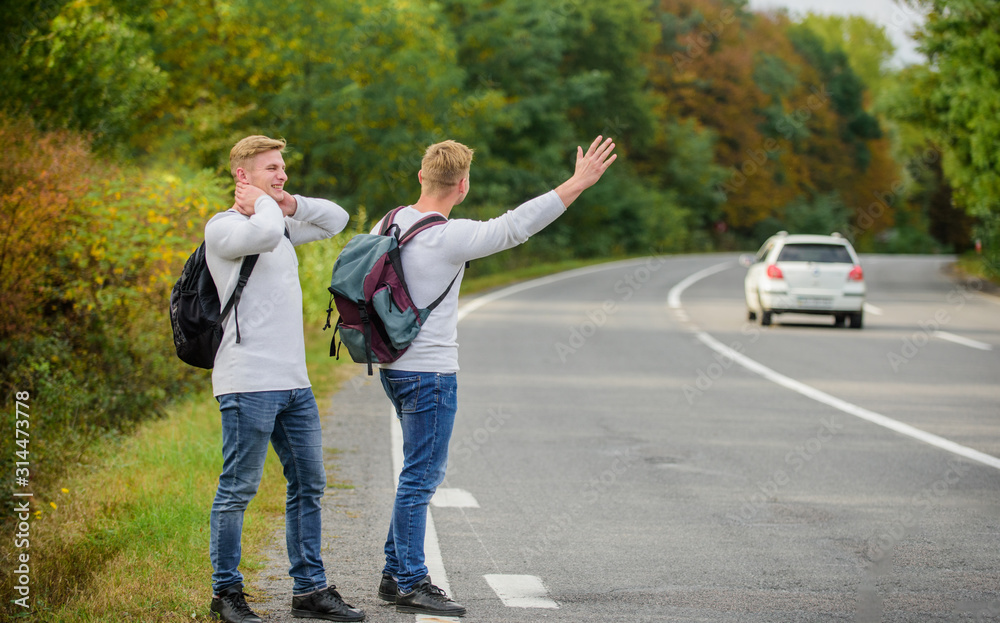 feeling of being free. twins walking along road. stop car with thumb up gesture. hitchhiking and stopping car with thumbs up gesture. On the road. Enjoying summer hike. Looking for transport feeling of being free. twins walking along road. stop car with thumb up gesture. hitchhiking and stopping car with thumbs up gesture. On the road. Enjoying summer hike. Looking for transport
