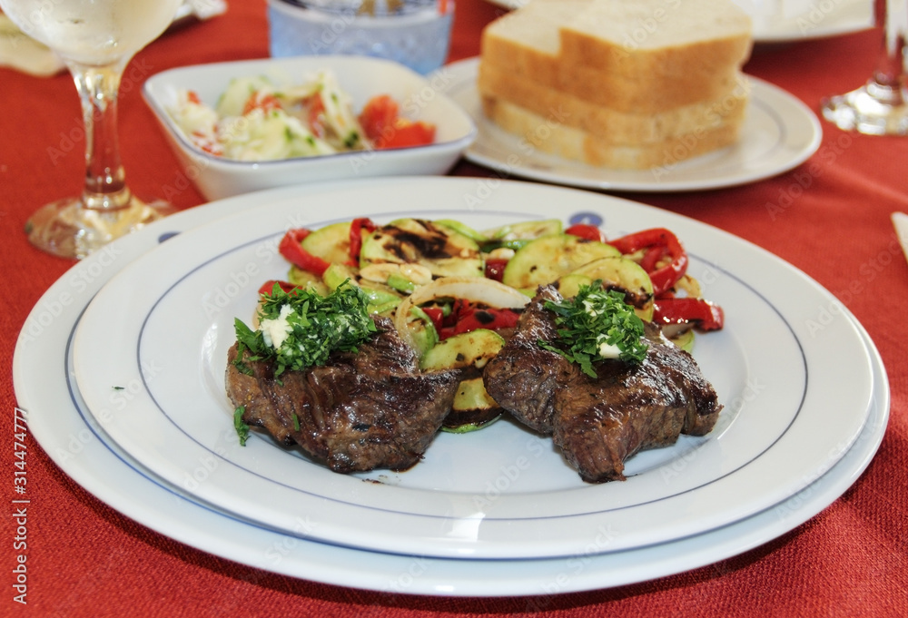 Roasted pork meat with grilled vegetables served on white plate.