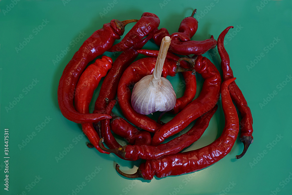 Fototapeta Red hot peppers in a pile in the shape of a circle with garlic in the center.