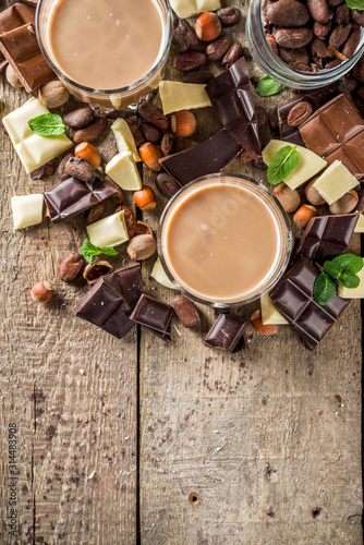 Sweet and strong alcohol drink. Chocolate liqueur with milk and dark chocolate pieces. Wooden background copy space