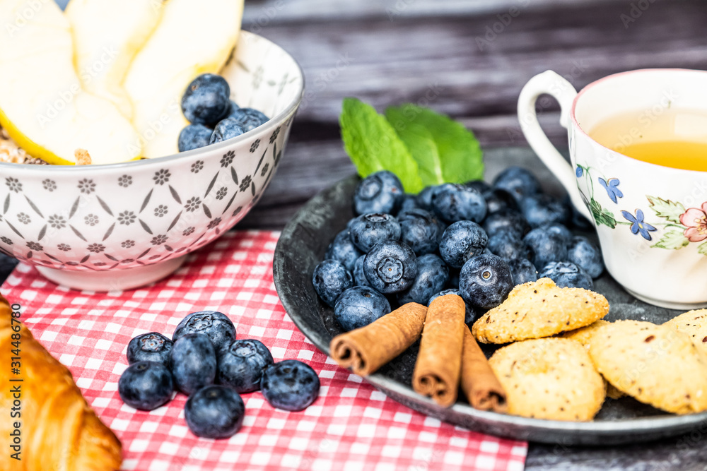 Petit déjeuner sain thé avec croissant biscuits cannelle muesli pommes et myrtilles Petit déjeuner sain thé avec croissant biscuits cannelle muesli pommes et myrtilles