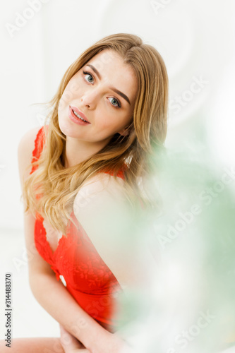 Sensual portrait of blonde woman in red lingerie indoor