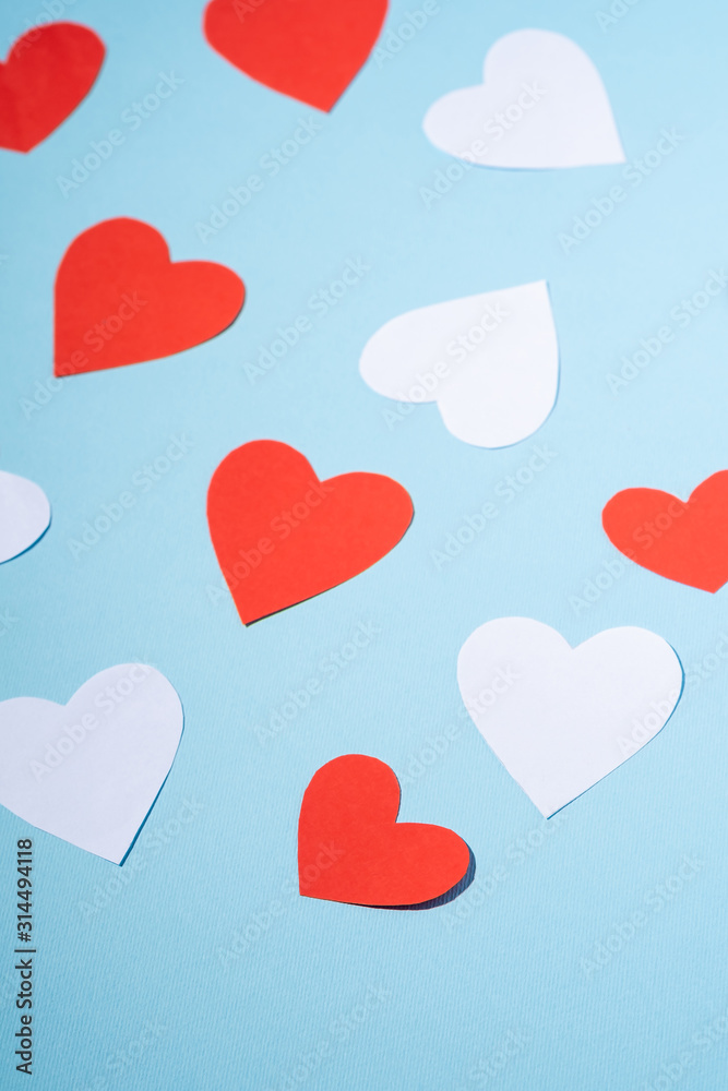 Red and white handmade paper hearts valentines on blue background, angle view, selective focus Red and white handmade paper hearts valentines on blue background, angle view, selective focus