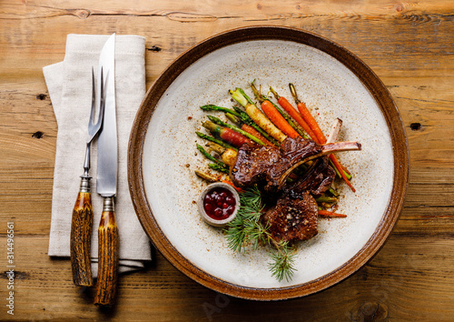 Canvastavla Grilled Venison Ribs with baked vegetables and berry sauce on wooden background