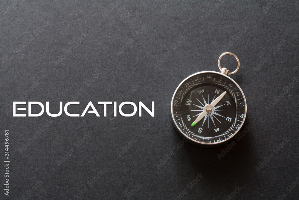 Education word written on black background with compass Education word written on black background with compass