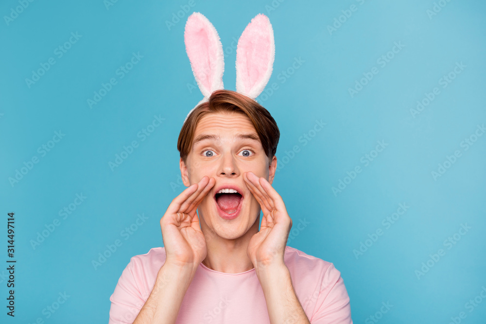 Closeup photo of amazing guy with funny bunny ears on head yelling novelty information spread gossips rumors people crowd wear casual pink t-shirt isolated blue color background Closeup photo of amazing guy with funny bunny ears on head yelling novelty information spread gossips rumors people crowd wear casual pink t-shirt isolated blue color background
