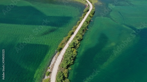 Aerial view of road over the Trebisnjica river  Lastva village  Bosnia and Herzegovina. Turquoise water  green bushes along the road. Minimalism.