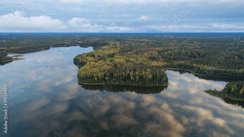 Autumn colored wild fores landscape and sunset cloud formations reflecting back from the calm water of the Ähijärv lake in Karula national park, Valga county, Estonia. photo