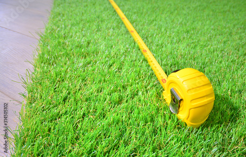 Artificial turf and measure tape lie on the laminate floor photo