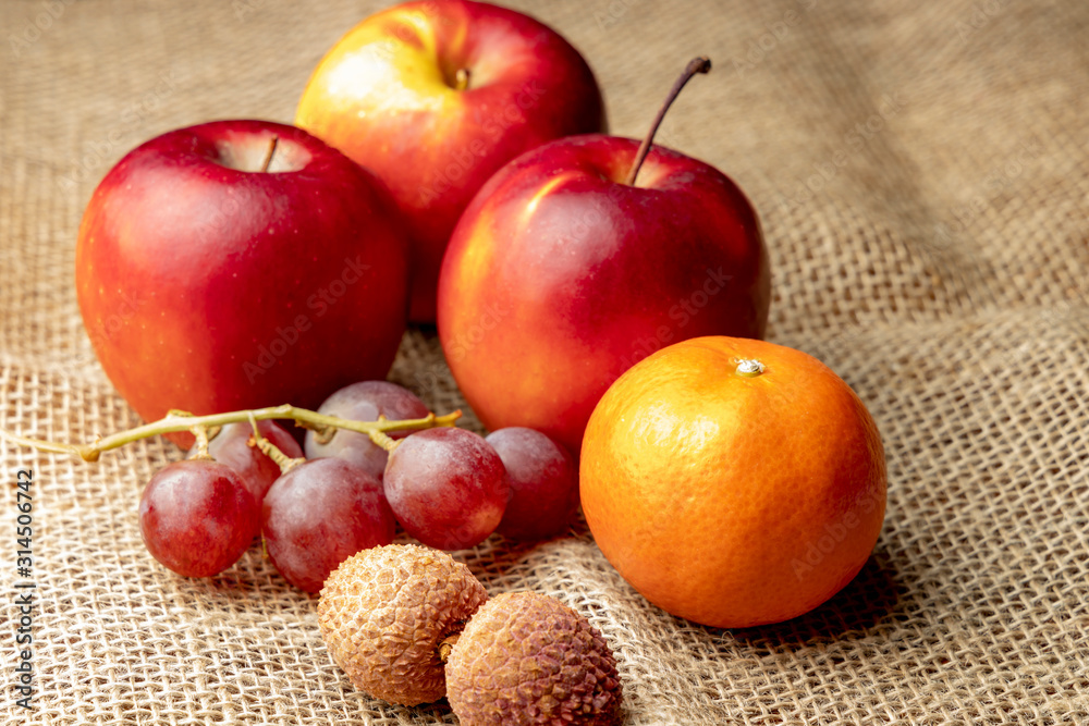 Three ripe red apples and other fruits on burlap. Three ripe red apples and other fruits on burlap.