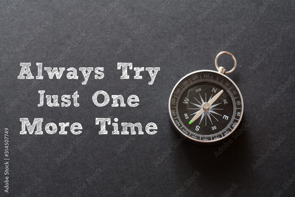 Written Always try just one more time words on black background with compass Written Always try just one more time words on black background with compass