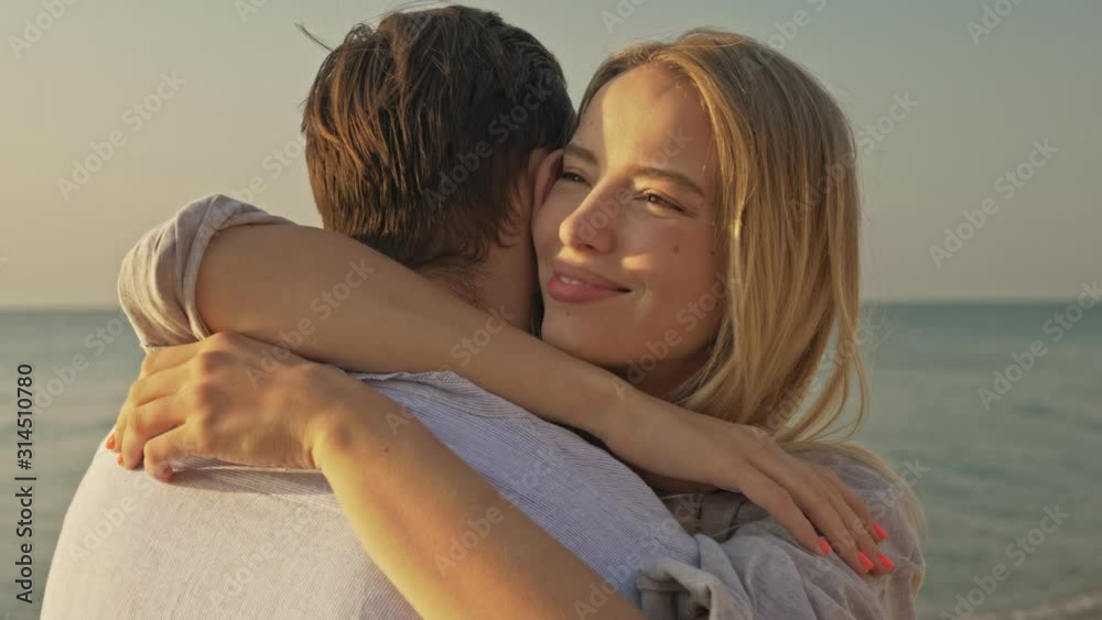 Lovely young couple man and woman are hugging each other at the beach