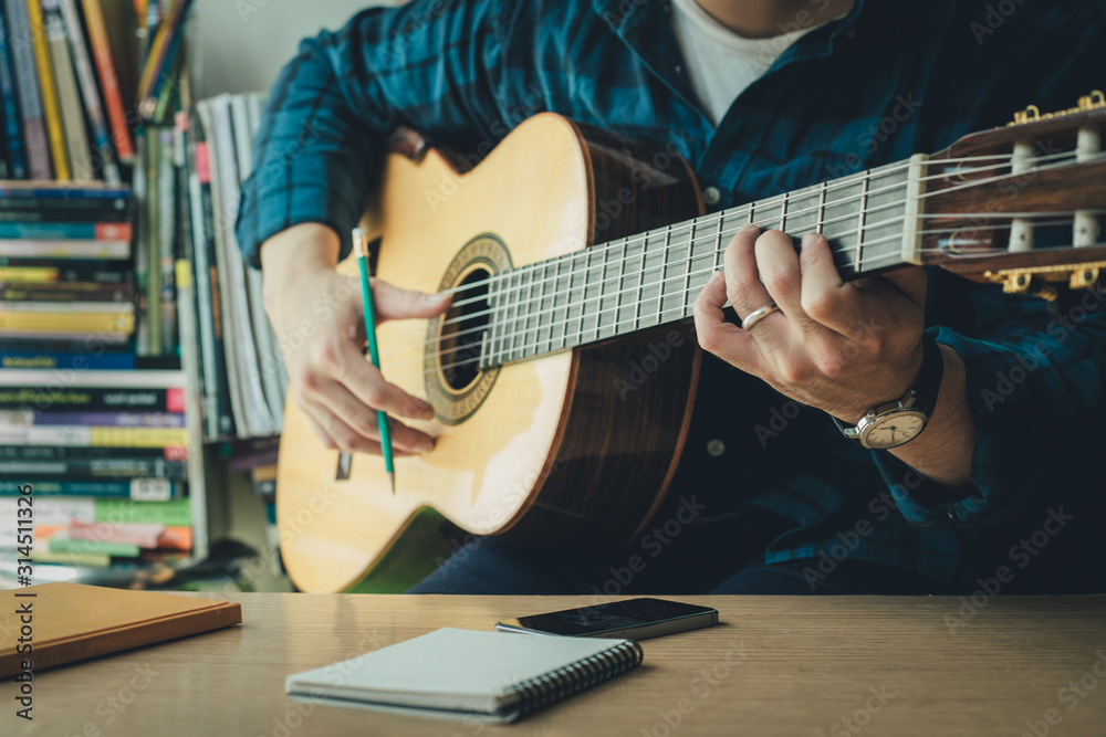 artist songwriter thinking writing notes,lyrics in book at studio.man playing live acoustic