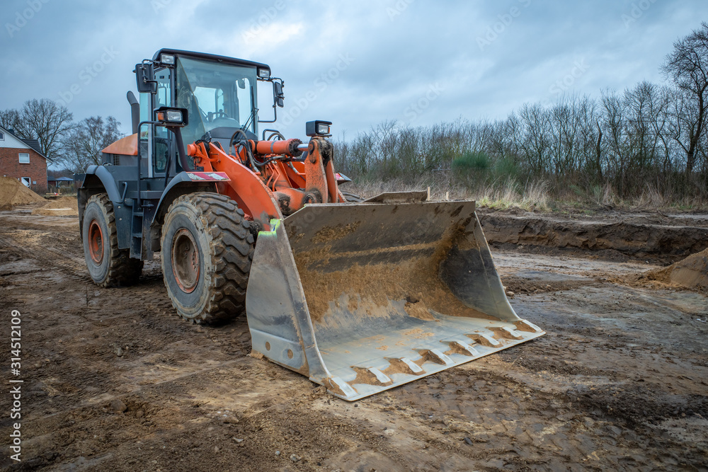 on a large construction site, excavators are used to remove topsoil so that a foundation for a large factory building can be built on a large construction site, excavators are used to remove topsoil so that a foundation for a large factory building can be built