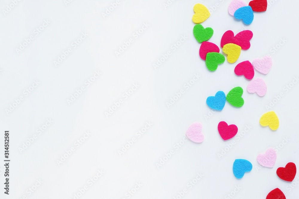 Colored small hearts on a white background. The concept of Valentine's Day, love, color therapy. Top view, flat lay with copy space for text.
