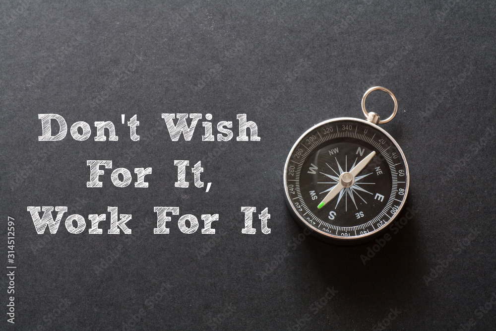 Written Don't Wish For It - Work For It words on black background with compass Written Don't Wish For It - Work For It words on black background with compass