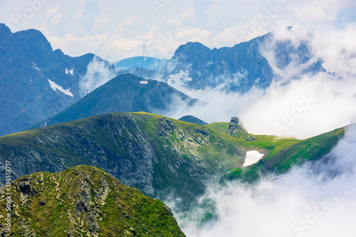 Fototapeta peaks of mountain ridge above the clouds