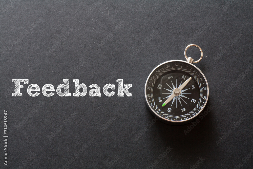 Written Feedback word on black background with compass Written Feedback word on black background with compass