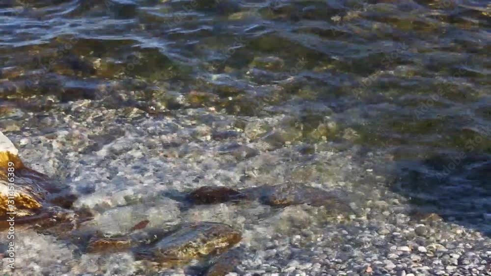 Movement of the transparent and clean water of Lake Garda. Close-up. Staycations concept of tourism in Italy. Movement of the transparent and clean water of Lake Garda. Close-up. Staycations concept of tourism in Italy.