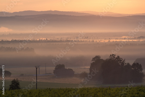 view over a misty valley with different shades of orange in the background