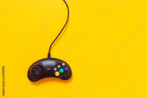 Black wired gamepad isolated on yellow