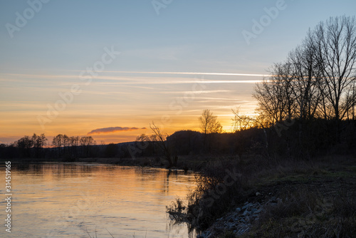 sunset near a lake with trees in the foreground