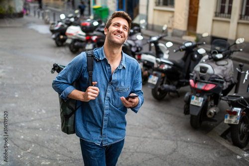 middle age man walking in city with mobile phone and bag