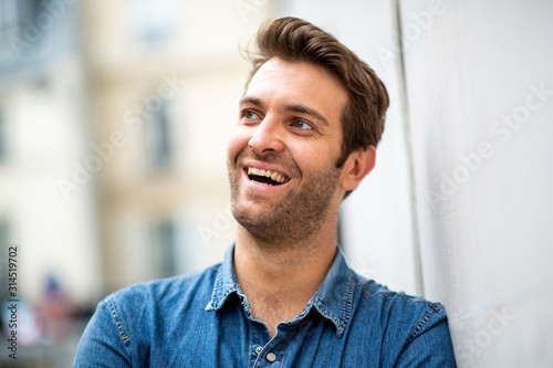 Close up older man leaning against wall and smiling while looking away