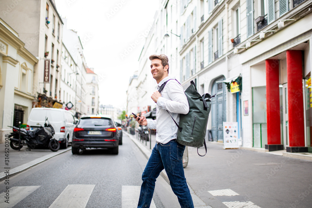 Side of happy man crossing street with mobile phone and bag Side of happy man crossing street with mobile phone and bag