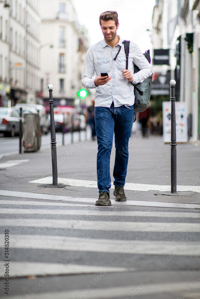 Full length happy travel man crossing street with mobile phone