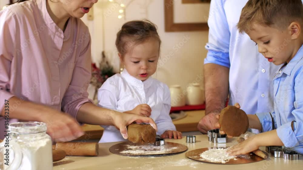Whole family is making cookies together for Christmas at xmas eve. Family of five people is preparing a dough for cookie Whole family is making cookies together for Christmas at xmas eve. Family of five people is preparing a dough for cookie